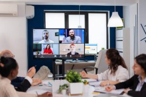 Office team joining remote colleagues via video conference in a modern meeting room.