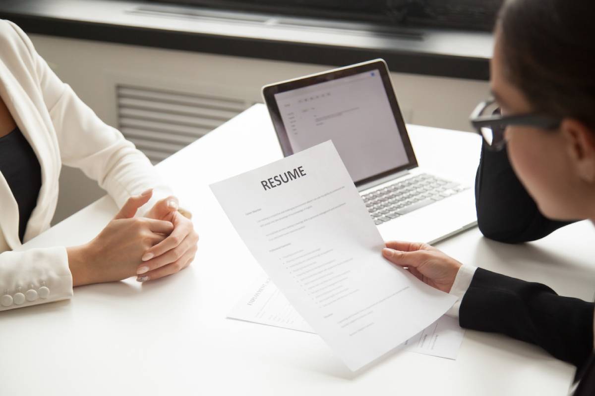  Job applicant and interviewer at a desk, reviewing a resume together during an interview.