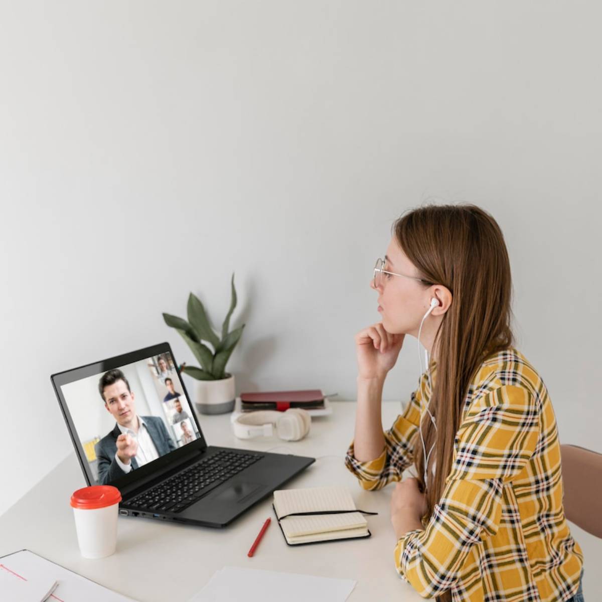 Woman in glasses attending a video call with a male colleague on her laptop at a tidy desk. 