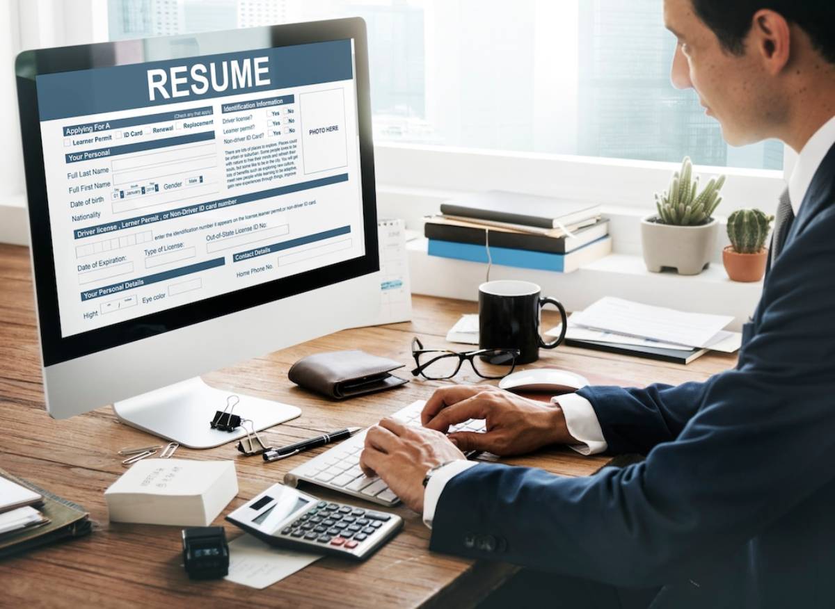 Businessman editing a resume on a computer screen in a modern office. 