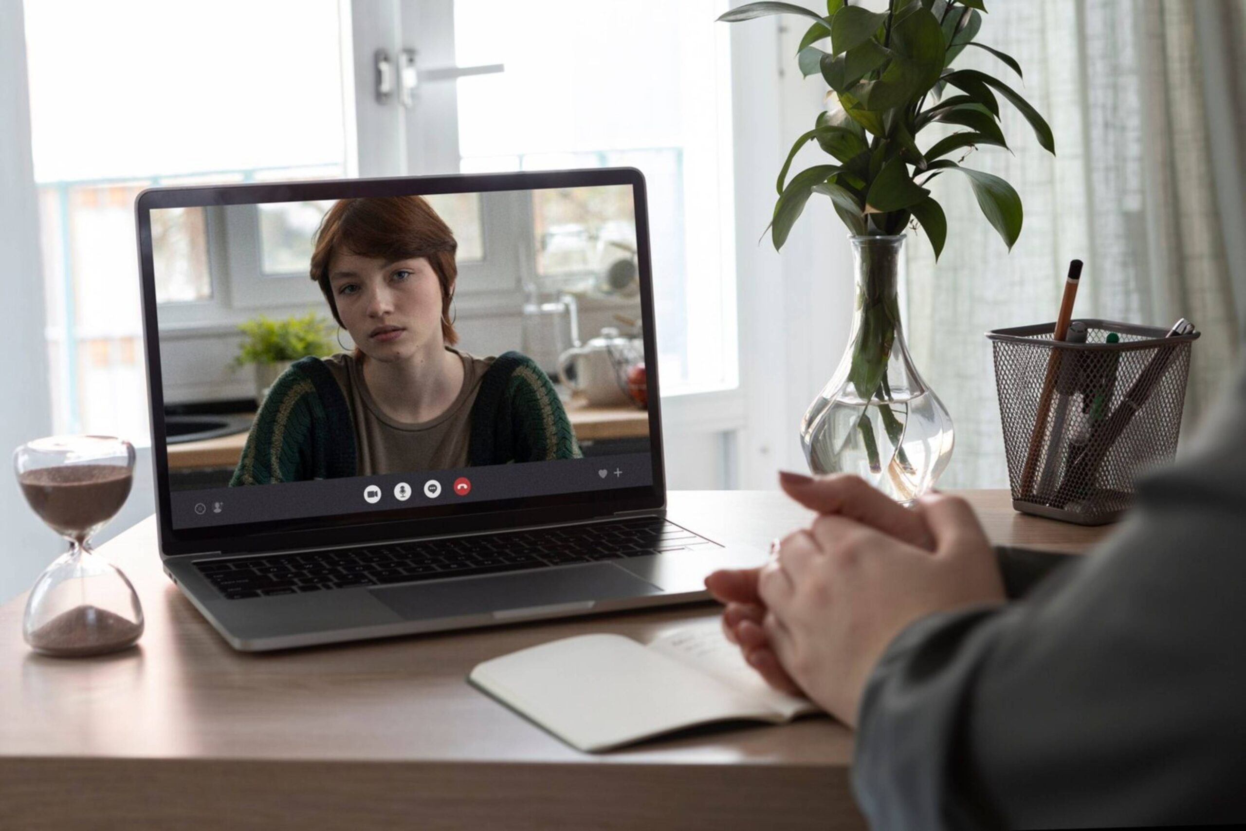 A person engages in a video call with a young woman displayed on a laptop screen. 
