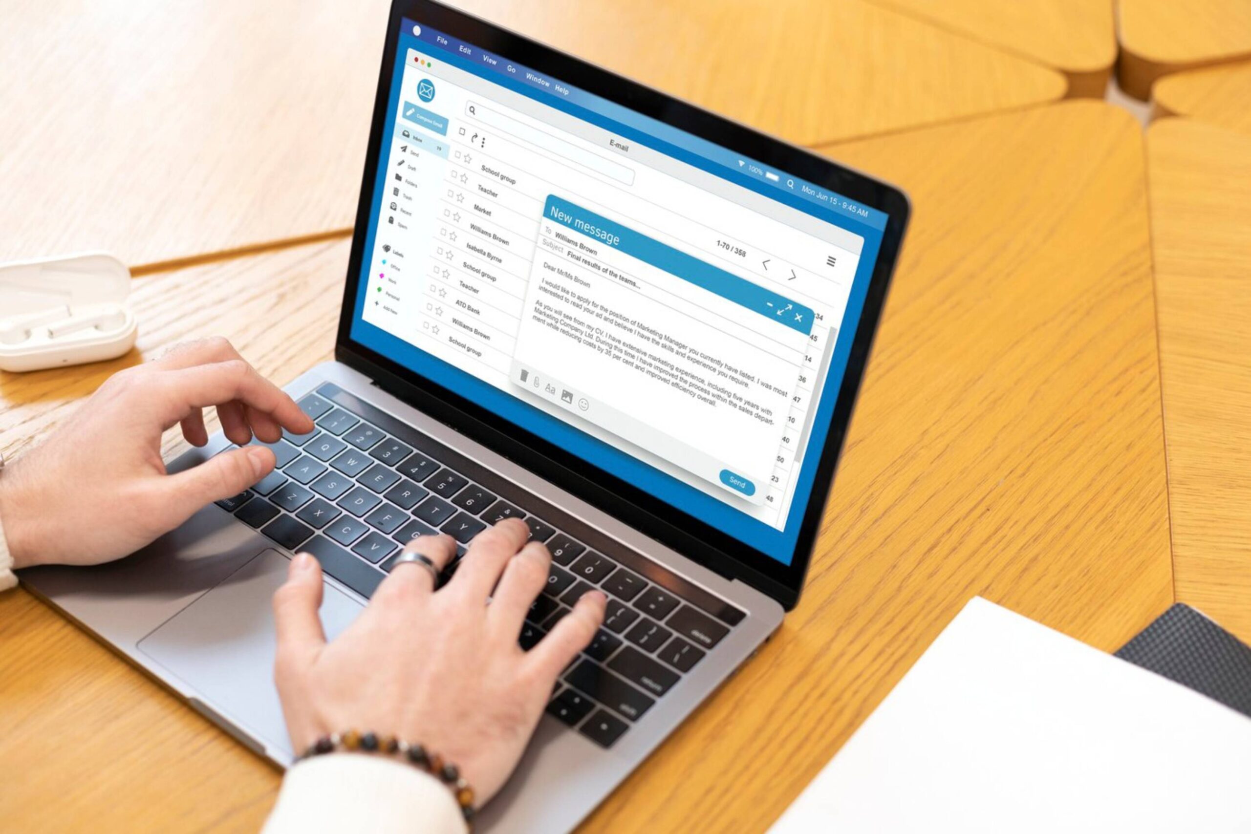  Person using a laptop to compose an email on a wooden table.