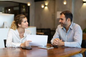 Two professionals discussing over a document in a modern office setting.