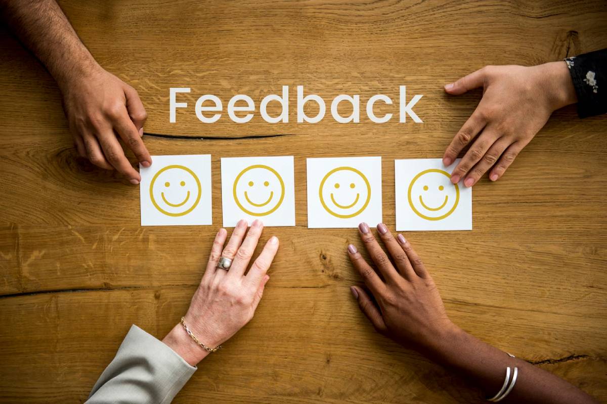  Four people placing their hands near smiley face cards on a wooden table with the word 